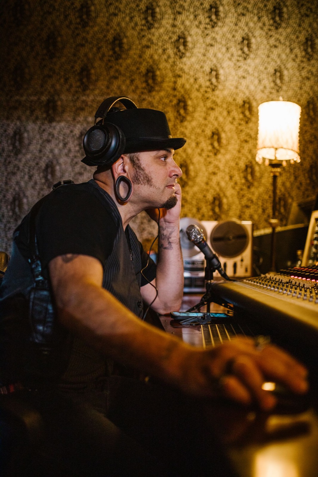 A producer in headphones at a mixing desk under a warm lamp